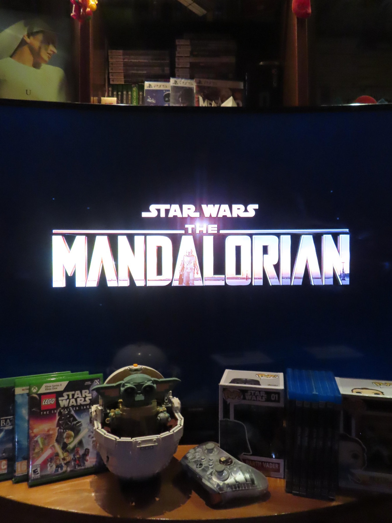 Mandalorian on a screen with Star Wars collectibles below